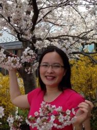woman in pink shirt holding cherry blossom branches