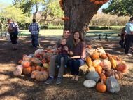 woman and man holding child in pumpkin patch